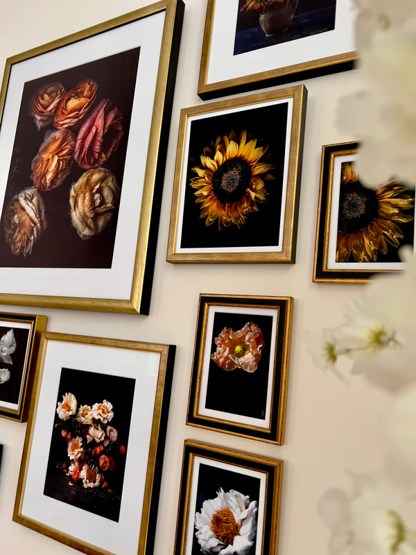 Gallery wall of framed floral art prints in home setting showing how flowers humanize spaces and nurture internal wellness